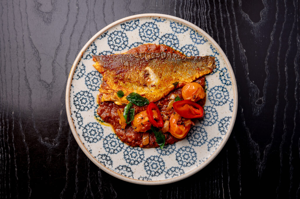 Sea Bass Pollichathu at Kerala Canteen Leeds with seared sea bass, tangy Kerala masala, and tempered cherry tomatoes